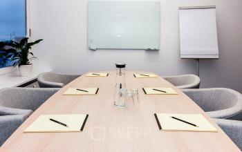 Heller Versammlungsraum mit gemütlichen Stühlen und Whiteboard an der Wand