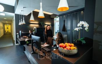 Modernes Büro in Neuer Wall 10, Hamburg Neustadt: Zwei Personen am Empfang arbeiten an Computern. Elegante Einrichtung mit dunklen Möbeln und stilvoller Beleuchtung, ideal zum Büroraum mieten.