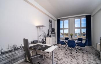 Moderner Büroraum mit großen Fenstern, ausgestattet mit Schreibtisch und Stühlen, ideal um Bürofläche in Hamburg Neustadt zu mieten.