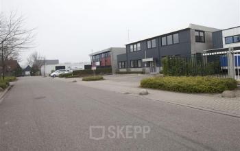Exterior view of office space rental at Techniekweg 2, Harmelen, featuring modern industrial design with surrounding greenery and ample parking.