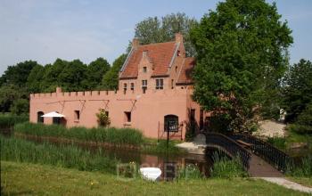 Charming exterior view of office space rental at Techniekweg 2 in Harmelen, featuring a unique brick building with a tranquil pond and bridge in the foreground.