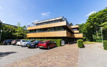 Exterior view of an office space rental at Herenweg 115, Heemstede, featuring a modern building with ample parking area.
