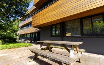 Exterior view of the office building at Herenweg 115, Heemstede, featuring wooden paneling and picnic tables, ideal for office space rental.