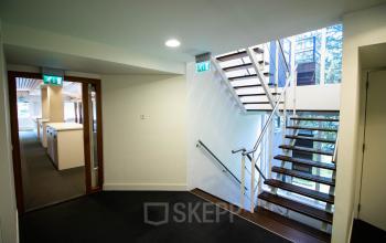 Interior view of an office space featuring a modern staircase and hallway at Herenweg 115, Heemstede, ideal for rent. The area connects to various office rooms.