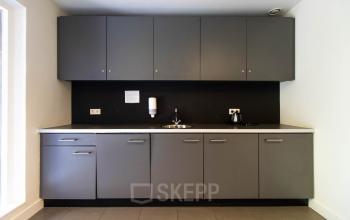 Compact kitchenette inside an office space rental at Herenweg 115, Heemstede, featuring grey cabinets and a sink.