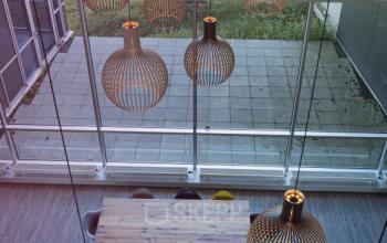 Spacious, well-lit office space rental at Snellius 1, Heerlen, with modern hanging lights and large windows overlooking a courtyard.