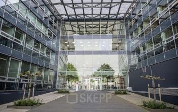 Exterior view of the modern Snellius 1 office building in Heerlen, with large glass windows and a spacious entrance.