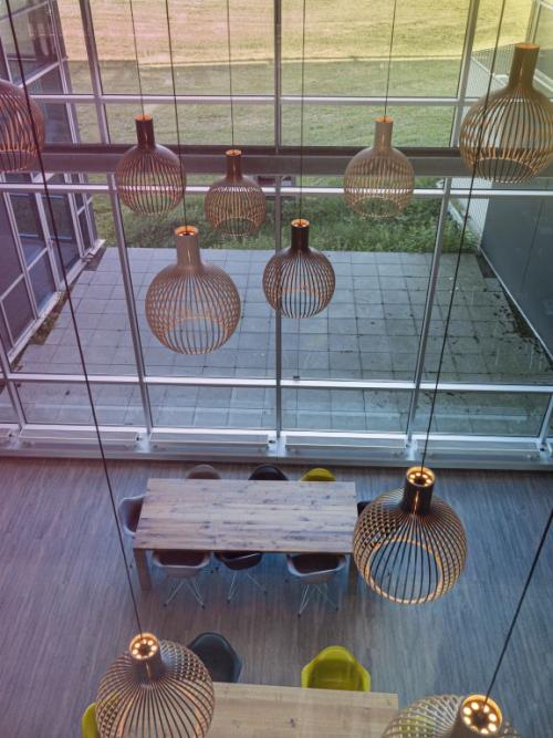 Spacious, well-lit office space rental at Snellius 1, Heerlen, with modern hanging lights and large windows overlooking a courtyard.