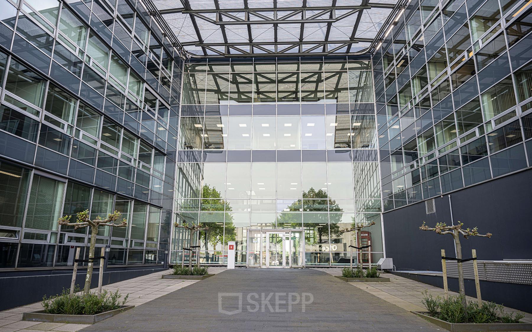 Exterior view of the modern Snellius 1 office building in Heerlen, with large glass windows and a spacious entrance.