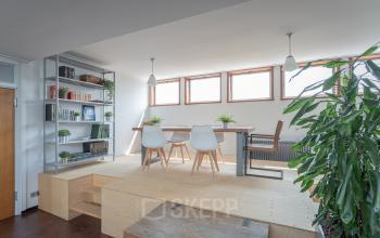 Modern office space for rent at Oliemolenstraat 60, Heerlen, featuring a bright area with wooden floors and large windows, furnished with desks and chairs.