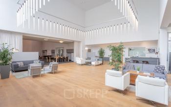 Spacious furnished office space with high ceilings, modern seating areas, and contemporary lighting at Oliemolenstraat 60, Heerlen, ideal for office to rent.