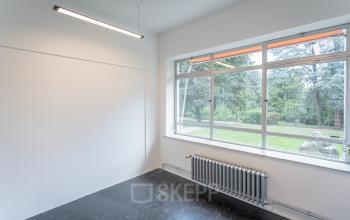 Interior of an office space at Oliemolenstraat 60, Heerlen with a large window providing natural light and a view of greenery.