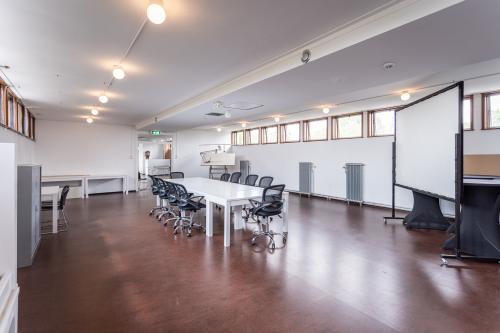 Spacious office space rental at Oliemolenstraat 60, Heerlen, featuring multiple desks, chairs, and a projector screen for presentations.