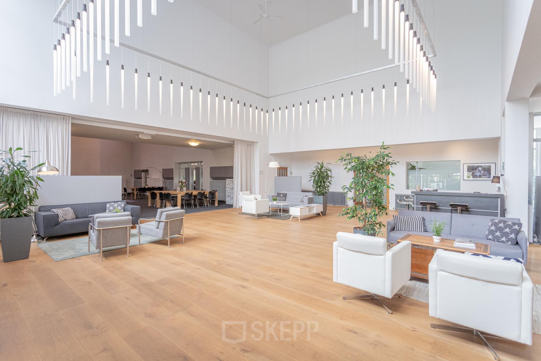 Spacious furnished office space with high ceilings, modern seating areas, and contemporary lighting at Oliemolenstraat 60, Heerlen, ideal for office to rent.
