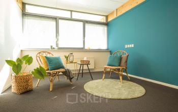 Bright, furnished office space with two wicker chairs, a round rug, and a large window at Steenovenweg 5 in Helmond.