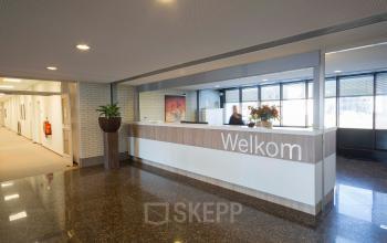 Reception area in an office building at Steenovenweg 5, Helmond, with a front desk, plants, and welcoming signage.
