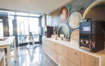Modern and bright pantry area in the office building at Steenovenweg 5, Helmond, featuring coffee machines and a large wall mural.