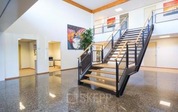 Modern reception area in the office building at Steenovenweg 5, Helmond with a sleek staircase, decorative wall art, and clean lines. Ideal for office space rental.