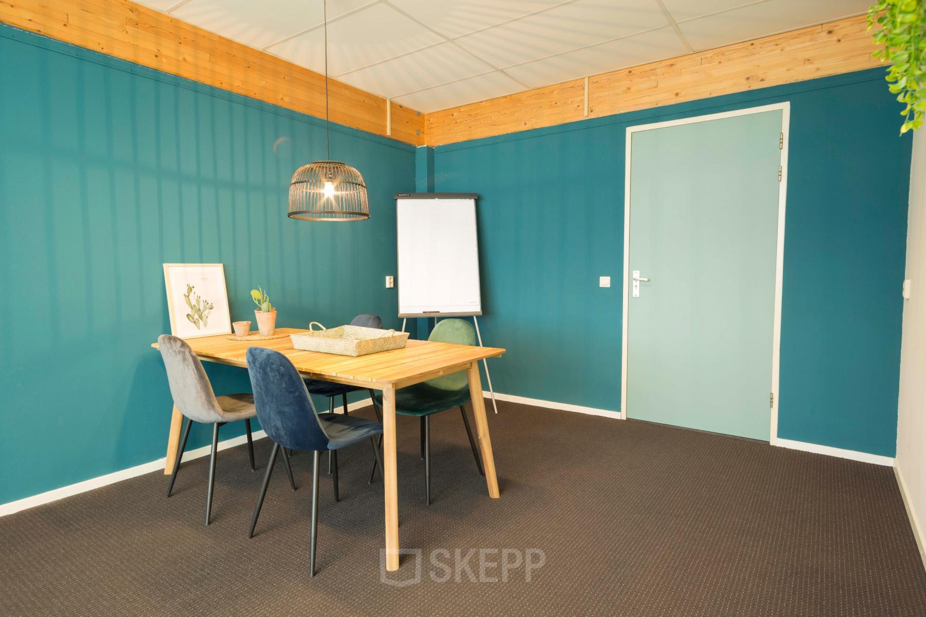 Office space at Steenovenweg 5, Helmond, featuring a meeting table with chairs, flipchart, and modern decor.