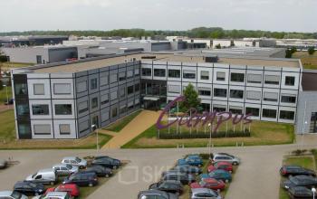 Elevated view of a modern office space rental at Jan Tinbergenstraat 202, Hengelo, with a parking area in the foreground.