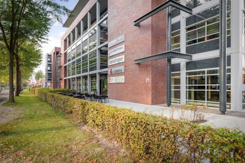 Exterior view of an office building located at Demmersweg 21-37, Hengelo, featuring modern architecture with large windows and outdoor seating area.