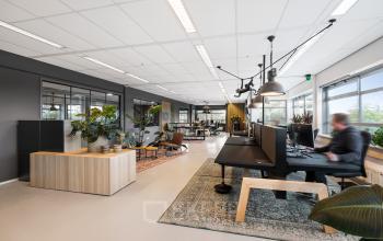 Modern office space rental at Hazenweg 2 2 in Hengelo, featuring spacious desks, indoor plants, and natural light.