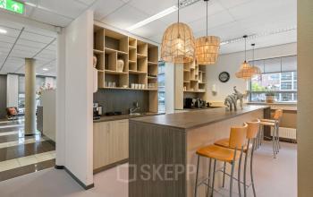 Modern, furnished pantry with wooden barstools, hanging lights, and coffee station at office to rent in Hazenweg 2 2, Hengelo.