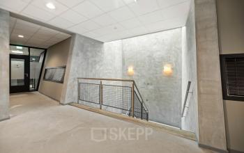 Office building interior at Lintelerweg 40, Hengelo, featuring a modern staircase with concrete walls and ceiling lights.