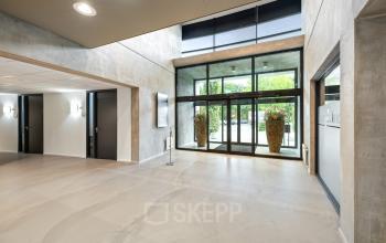 Modern office entrance at Lintelerweg 40 in Hengelo with large glass doors and minimalist decor.
