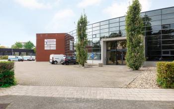Exterior of the office building at Lintelerweg 40, Hengelo featuring large glass windows, a modern design, and spacious parking area. Ideal for office space rental.