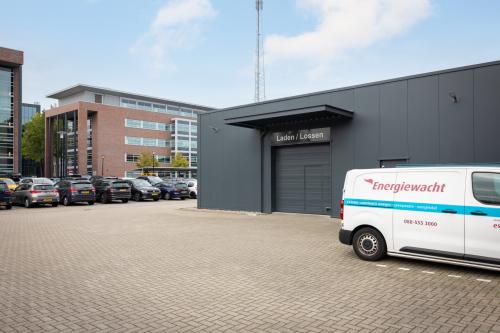 Exterior view of the office building at Lintelerweg 40, Hengelo, with parking area and several cars.