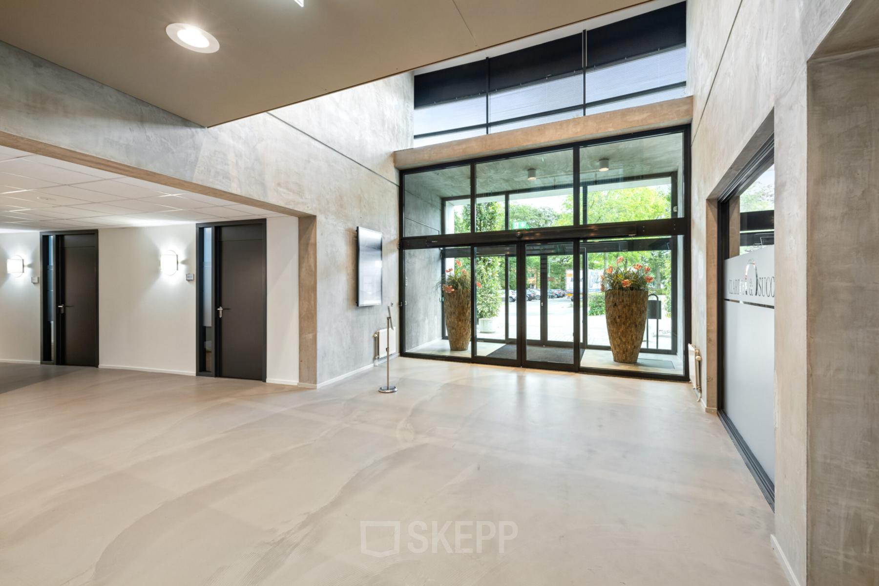 Modern office entrance at Lintelerweg 40 in Hengelo with large glass doors and minimalist decor.