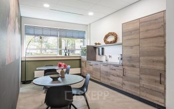 Modern pantry at an office to rent at Demmersweg 41-47, Hengelo, featuring wooden cabinets, tables, and chairs.