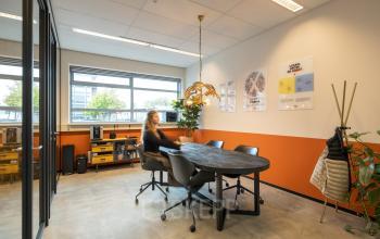 Bright office interior at Demmersweg 41-47, Hengelo, featuring a modern workspace with a large table, chairs, and wall art, perfect for an office to rent.