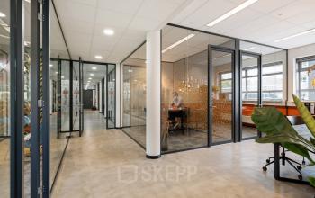 Modern glass-partitioned office space with a person working at a desk, situated at Demmersweg 41-47, Hengelo.