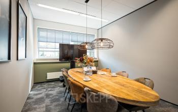 Modern conference room at Demmersweg 41-47, Hengelo, featuring a large wooden table, comfortable chairs, and a flat-screen TV suitable for professional meetings.