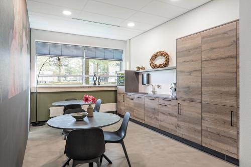 Modern pantry at an office to rent at Demmersweg 41-47, Hengelo, featuring wooden cabinets, tables, and chairs.