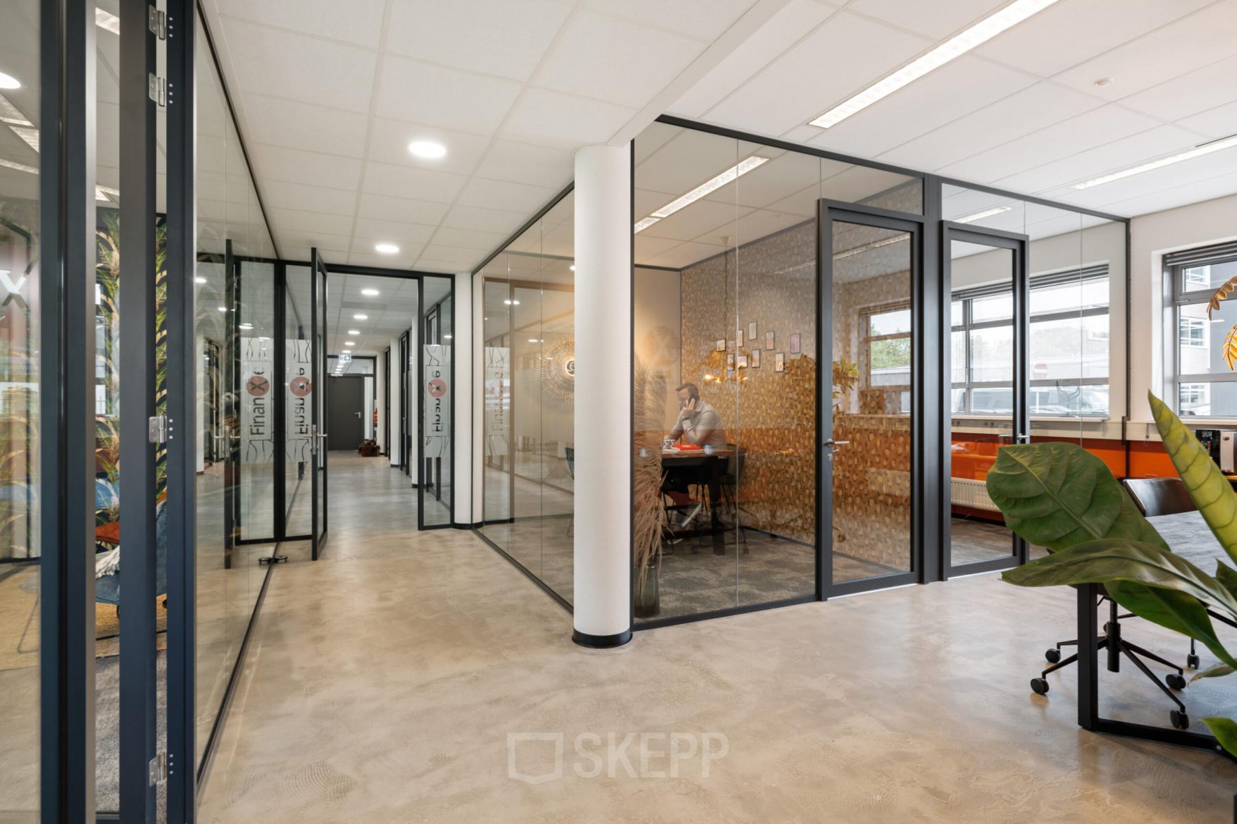 Modern glass-partitioned office space with a person working at a desk, situated at Demmersweg 41-47, Hengelo.