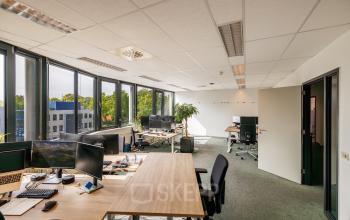 Bright and contemporary office space with workstations, large windows, and modern furnishings at Welbergweg 60, Hengelo. Ideal for businesses seeking office space rental with natural light and functional design.