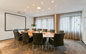 Spacious office to rent at Welbergweg 60, Hengelo, featuring a large meeting table surrounded by sleek chairs and ample natural light.