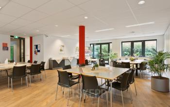 Bright office space at Welbergweg 60 in Hengelo featuring wooden floors, tables, chairs, and potted plants, ideal for office space rental.