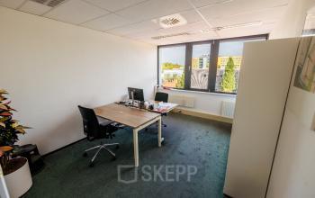Bright office space at Welbergweg 60 in Hengelo with large window, furnished with desks and chairs, ideal for those looking for an office to rent.