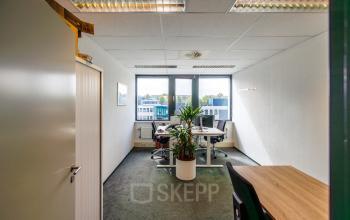 Interior view of an office space available for rent at Welbergweg 60, Hengelo, featuring desks, chairs, and natural light through large windows.
