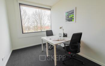 Modern office space at Atealaan 34A, Herentals, with large window, two desks, chairs, and phone; ideal for office space rental.