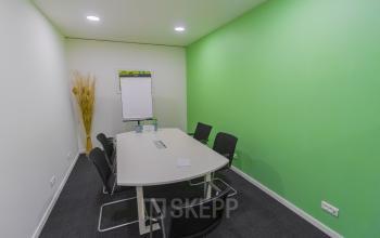 Conference room at Atealaan 34A, Herentals, featuring a green accent wall, large table, and chairs. Ideal for office space rental.