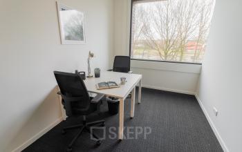Minimalist office space with a large window, two desks, and chairs located at Atealaan 34A, Herentals.