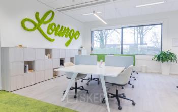 Modern office interior at Atealaan 34A, Herentals, featuring collaborative workspaces with stylish furnishings, green accents, and ample natural light. Ideal for businesses seeking office space rental in a vibrant setting.