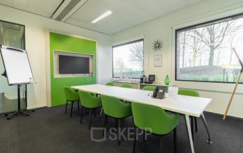 Modern office space rental at Atealaan 34A, Herentals featuring a conference room with a white table, green chairs, and large windows providing natural light.