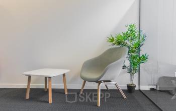 Modern furnished office space with a single chair, small table, and potted plant at Atealaan 34A, Herentals, available for office space rental.