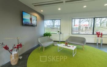 Modern interior lounge area at Atealaan 34A, Herentals, featuring comfortable seating and a green rug, available for office space rental.